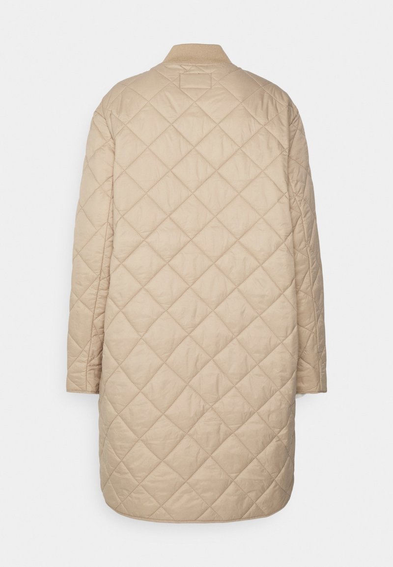 Manteau long beige matelassé avec motif de piqûres en losange, col côtelé et manches longues, vu de dos sur un fond blanc.