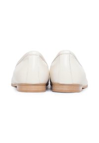 Scarpe in pelle bianca con una suola piatta di colore marrone chiaro. Il design presenta una punta arrotondata e cuciture minime lungo le giunture.