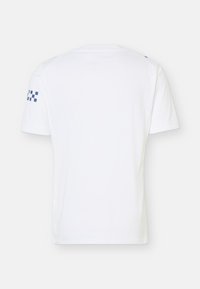 Λευκό κοντομάνικο T-shirt με στρογγυλή λαιμόκοψη και μικρό μπλε καρό μοτίβο στο αριστερό μανίκι, εμφανιζόμενο από πίσω σε ουδέτερο φόντο.