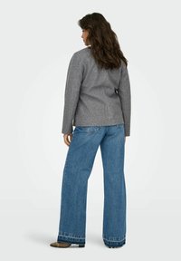 Grijze gebreide trui met een aansluitend ontwerp, gecombineerd met wijde spijkerbroek in blauw met een rafelig zoom en contrasterende stiksels.