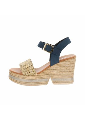 Sandale compensée avec bride avant beige tissée, bride de cheville bleu marine avec boucle dorée et semelle en corde naturelle texturée avec talon plateforme.