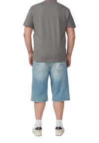 Grijze katoenen t-shirt, losse pasvorm, gecombineerd met lichtblauwe denimshorts, knielang, met achterzakken en vervaagd uiterlijk, gedragen met sneakers.