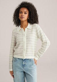 Pletený kardigán v smotanovej farbe s textúrovaným vzorom v mriežke, s golierovým výstrihom, piatimi gombíkmi a rebrovanými manžetami a lemom.