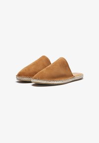 Brune ruskind slip-on mules med spids tå, der har en vævet jute sål og en glat tekstur. Enkel, minimalistisk design i neutralt farve.