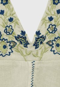 Embroidered blouse featuring a v-neck design with green and blue floral patterns, textured fabric, and beaded accents along the neckline.