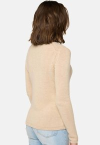 Beige gestrickter Pullover mit langen Ärmeln, ausgestattet mit einem gerippten Halsausschnitt und Saum. Glatte Textur und taillierte Passform mit einem dezent gewölbten Rücken.