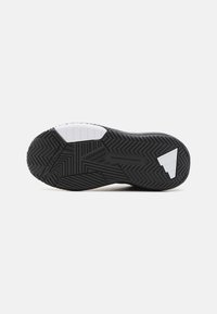 Schwarze Gummisohle von Sneakers mit strukturiertem Fischgrätenmuster, ausgestattet mit weißen Akzenten und geprägtem Branding. Entworfen in Los Angeles.