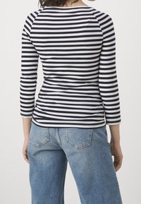 Randig långärmad topp i marinblått och vitt, figurnära silhuett. Matchad med ljusblå vida jeans, med fickor och klassisk design.