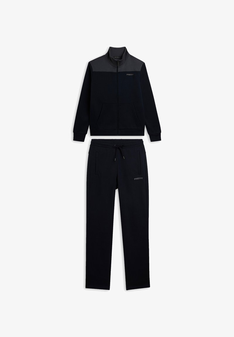 Chándal deportivo azul marino con chaqueta de cremallera que presenta un panel gris y bolsillos, combinado con pantalones a juego con cordón. Textura suave.