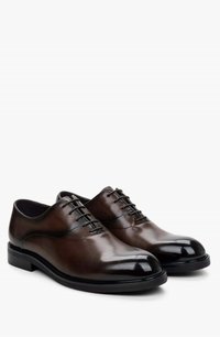 Brown leather lace-up shoes with a smooth finish, rounded toe, and contrasting glossy toe cap. Features thin laces and a sleek silhouette.