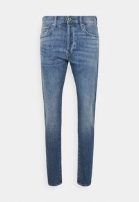 Ljusblå denimjeans har en slim fit, femfickorsdesign och knäppning med knapp. Tyget har en blekt tvättmönster och jämn textur.