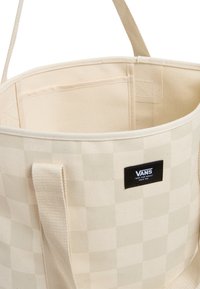 Borsa tote beige a quadri realizzata in materiale canvas, con un'etichetta nera Vans e due manici resistenti per un facile trasporto. L'interno include una tasca.