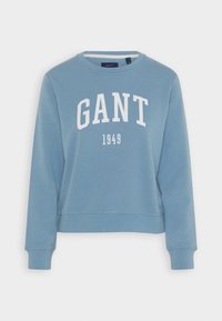 Felpa azzurra con colletto rotondo, maniche lunghe e stampa bianca "GANT 1949" sul davanti. Tessuto morbido, vestibilità casual.