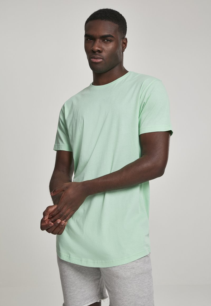 Lys grøn bomulds T-shirt med korte ærmer og rund halsudskæring, parret med grå shorts. Glat tekstur, afslappet pasform og ingen synlige mønstre.