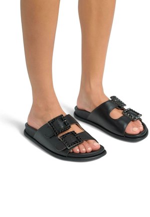 Zwarte leren slide-sandalen met twee decoratieve gespaccenten, een gladde textuur, open teenontwerp en een platte zool.