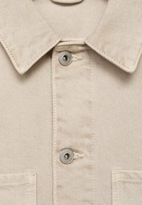 Beige denim shirt met een puntige kraag, zilveren drukknoopjes en twee borstzakken met zichtbare stiksels.