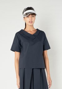 Top blu navy con maniche corte e scollatura a V, caratterizzato da un colletto ripiegato. Realizzato in un tessuto morbido e leggero.