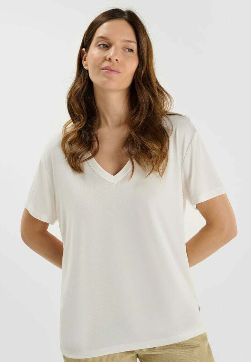 Witte v-hals t-shirt met korte mouwen, gladde textuur, losse pasvorm en minimale naaddetails. Gestyled met neutraalgekleurde onderkleding.