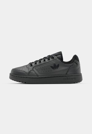 Sneaker in pelle nera con dettagli perforati, design con lacci, suola piatta in gomma e logo stampato sul lato. Estetica minimalista.