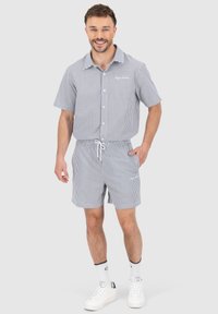 Striped short-sleeve shirt and matching shorts set in white and navy blue. Features a button-up front and an elastic waistband with drawstring.