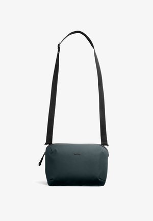 Kleine dunkelgrüne Umhängetasche mit verstellbarem schwarzem Riemen, Reißverschlussverschluss und "bellroy"-Logo in der Mitte vorne.