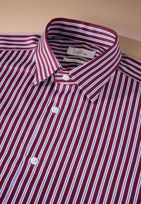 Bordeauxrot-weiß gestreiftes Hemd mit schmal geschnittener Passform, durchgehendem Kragen und zwei weißen Knöpfen vorne in der Nähe des Kragens.