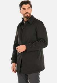 Cappotto nero monopetto con scollo a colletto, polsini con bottoni e tasche laterali, realizzato in un tessuto liscio e strutturato.