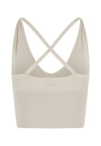 Beige naadloze sport-bh met een geribbelde textuur, voorzien van een lage rug en kruisslingerende bandjes. Logo gecentreerd op de voorkant.