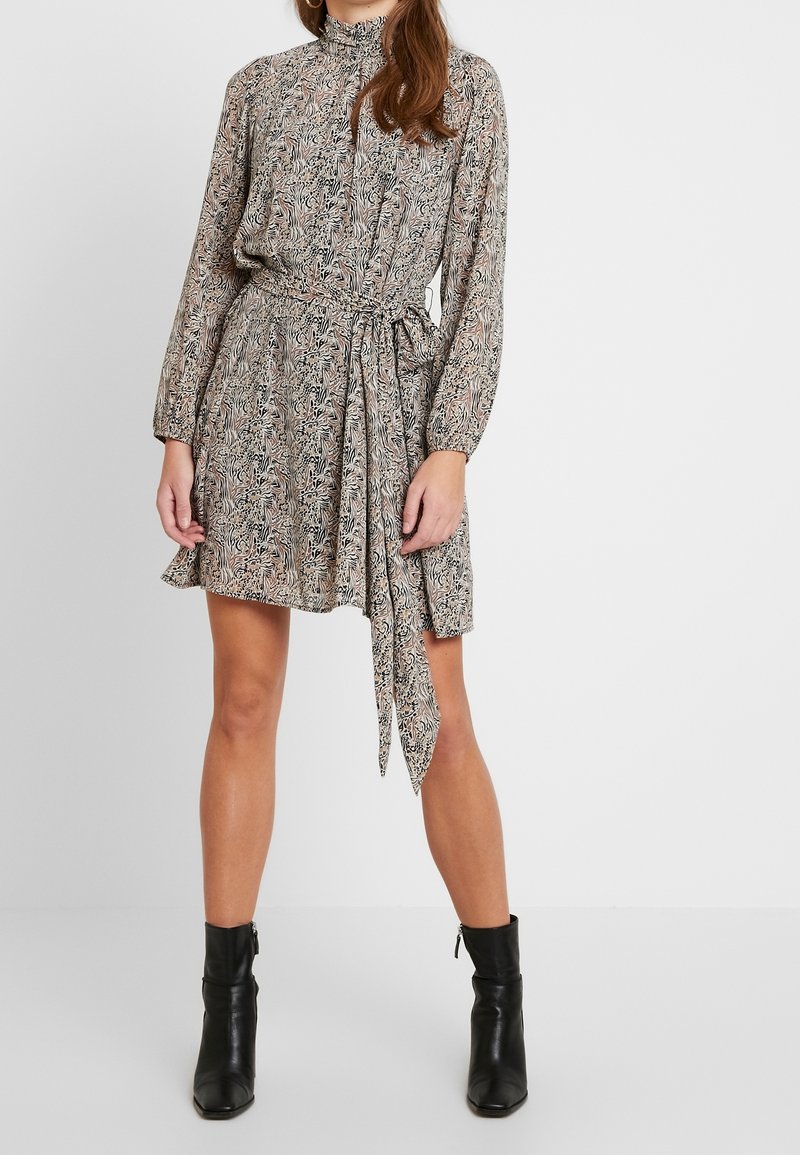 Vestido estampado en tejido ligero, con cuello alto, mangas largas, cintura con cinta y una falda acampanada con un patrón mezclado en beige y negro.