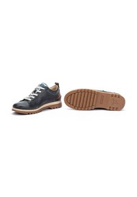 Black leather sneakers with beige rubber soles, featuring white laces, a blue accent on the tongue, and a textured tread pattern.