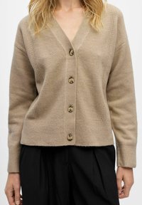 Beige wool cardigan with a V-neck, featuring six brown buttons, ribbed hem, and subtle vertical stitch detailing along the seams.