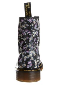 Blommig ankelsko med svart bakgrund, prydd med lila och gula blommor. Texturerat läder med en robust sula och gula sömdekorationer.