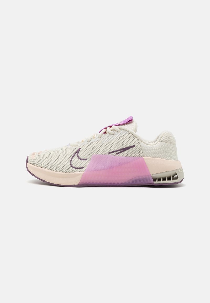 Chaussure de sport beige clair et rose pastel avec des accents violets, tige en mesh, et une semelle rembourrée avec un support aérien visible au talon.