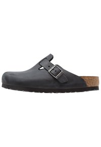 Sabot en cuir noir à bout couvert, sangle ajustable avec boucle, semelle en liège et semelle en caoutchouc texturé pour une meilleure adhérence.