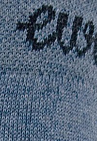 Tissu tricoté bleu texturé avec des lettres noires partiellement visibles. Le motif présente un design doux et respirant.