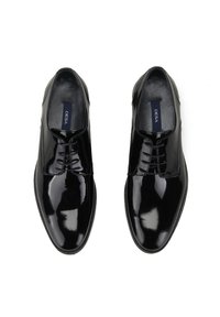 Chaussures habillées en cuir verni noir avec un design épuré, bout arrondi et lacets fins. L'intérieur présente une doublure noire lisse et une semelle intérieure avec la marque.