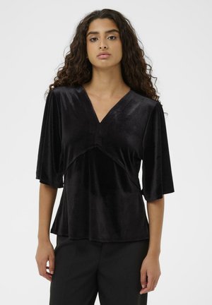 Schwarzes Samtoberteil mit V-Ausschnitt, ¾-Ärmeln und einem schrägen Nahtdetail in der Taille, das einen sanften Fall und eine glatte Textur erzeugt.