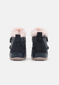 Bottes de cheville bleu foncé avec doublure en fausse fourrure rose, sangle Velcro et matériau en daim texturé. Semelle en caoutchouc robuste avec un léger saupoudrage.