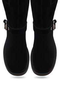 Crne antilop čizme do koljena s glatkom završnom obradom, ukrašene remenom i kopčom na vrhu. Okrugli vrh i dizajn s niskom petom.