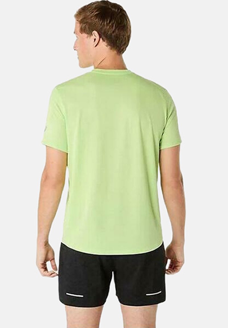 T-shirt verde chiaro a maniche corte con scollo tondo, abbinato a pantaloni corti neri con dettagli bianchi. Il tessuto appare liscio e leggero.