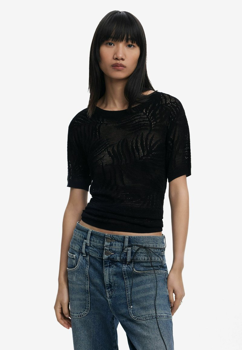 Top nero in maglia con un motivo testurizzato, maniche corte e vita aderente, abbinato a jeans di denim blu a vita alta con cuciture a contrasto.