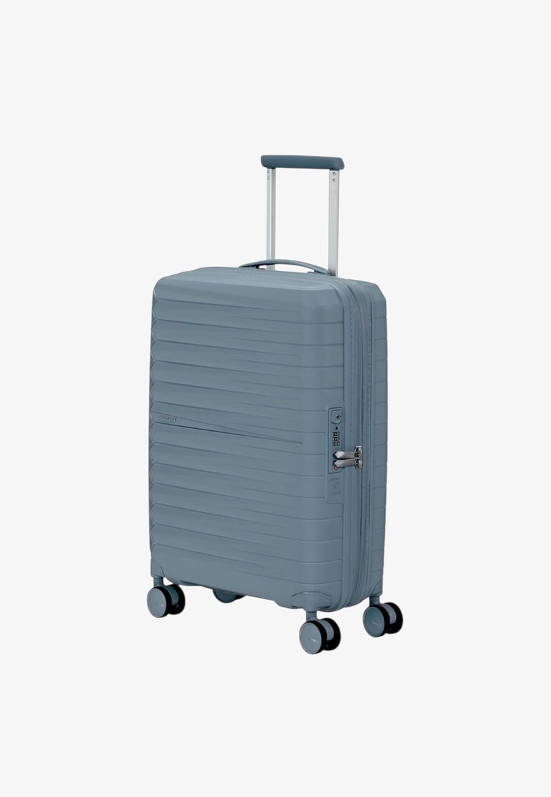 Valigia rigida di colore blu chiaro, caratterizzata da una texture a righe, manico telescopico e quattro ruote girevoli per una facile manovrabilità.