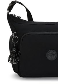 Borsa a spalla nera realizzata in tessuto durevole con una superficie testurizzata, dotata di una tasca con zip, etichetta del logo e un piccolo accessorio portachiavi.