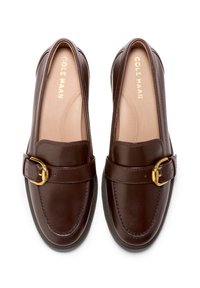 Bruna läderloafers med ett spänne i guldton, rund tå och vadderad innersula. Slät textur med stickningsdetaljer längs kanterna.