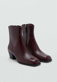 Botines de cuero burdeos con puntera cuadrada, tacón bajo en bloque y detalle de cremallera lateral. Superficie lisa con un acabado pulido.