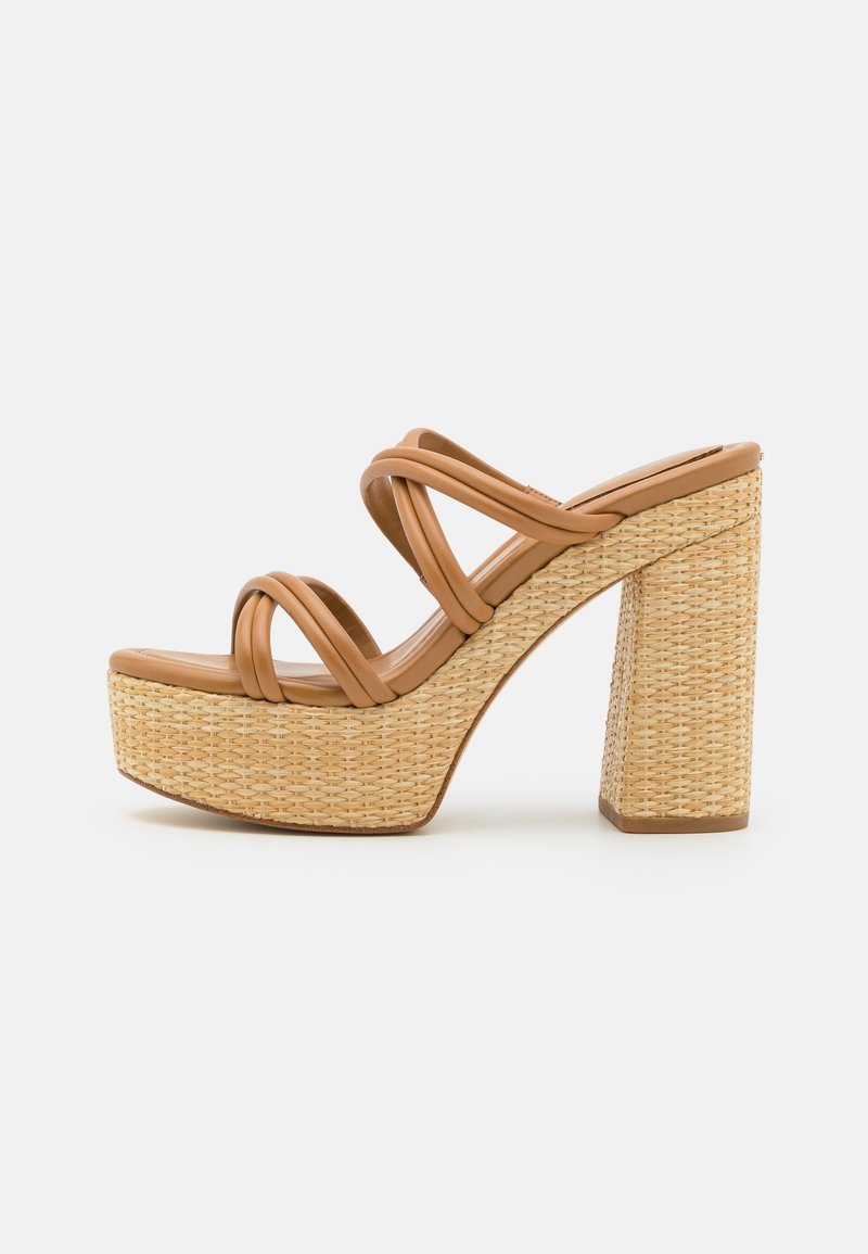 Sandalia de plataforma con tacón alto y base de paja trenzada, con tiras de cuero marrón entrelazadas, sobre fondo blanco liso.