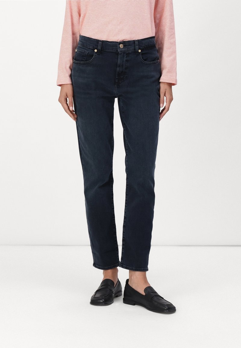 Jeans de mezclilla azul oscuro con un corte recto. Las características incluyen un cierre de botón y cremallera, cinco bolsillos y sutiles detalles de costura.