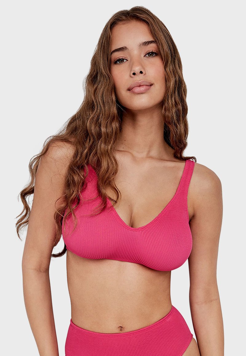 Top de bikini de color rosa con canalé que presenta un escote en V profundo y tirantes anchos. La tela tiene un acabado texturizado, complementando un fondo a juego.