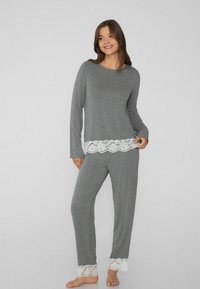 Pijama gris de manga larga con pantalones a juego, presenta un encaje blanco en el dobladillo. Tela suave y lisa con un corte relajado.