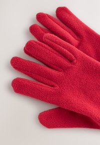 Gants rouges en polaire avec une texture douce, cinq doigts et un ajustement confortable. Le tissu semble chaud et adapté aux temps froids.